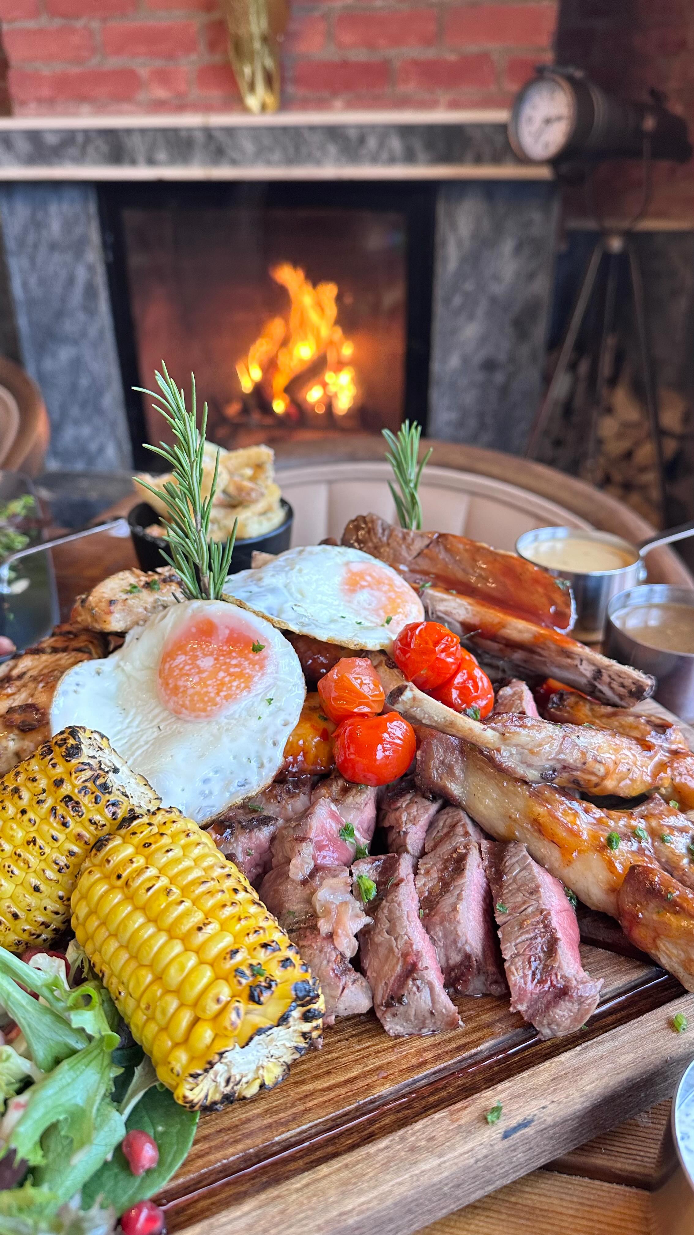 Breakfast board with corn, eggs and steak by the fire